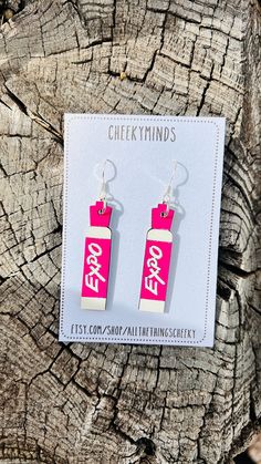 pink and white earrings with chinese characters on them sitting on top of a piece of wood