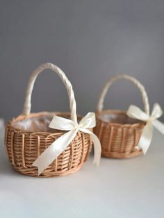 two wicker baskets with white ribbons tied around the handles, one has a bow on it