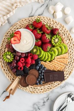 a platter filled with fruit, chocolate and marshmallows on a marble table