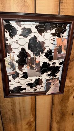 a cow print mirror hanging on the side of a wooden wall