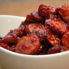 a white bowl filled with cooked meat on top of a wooden table next to a fork