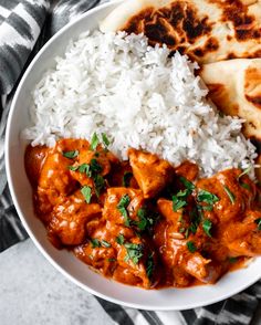 a white plate topped with rice and meat covered in sauce next to pita bread