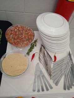 a table topped with lots of white plates and silverware