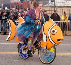 a woman riding on the back of a bike decorated with clown fish decorations and beads