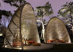 an outdoor seating area is lit up at night with lights on the trees in the background