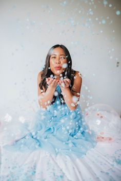 a woman sitting on top of a bed surrounded by confetti