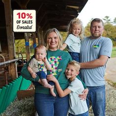 a family posing for a photo in front of a barn with the sale sign 10 % off