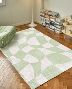 a green and white rug on the floor in front of a lamp with bookshelves behind it