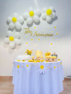 a table topped with cake and desserts next to a wall decorated with daisies