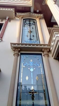 an ornate stained glass window on the side of a building with columns in front of it