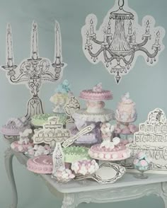 a table topped with lots of cakes and cupcakes next to a chandelier