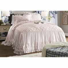 a bed with pink ruffled bedspread and pillows