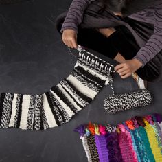 a woman sitting on the floor next to some knitted items