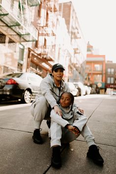 a woman and child sitting on the sidewalk