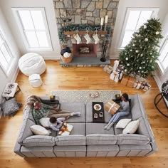 two people sitting on a couch in front of a fire place with christmas trees and presents