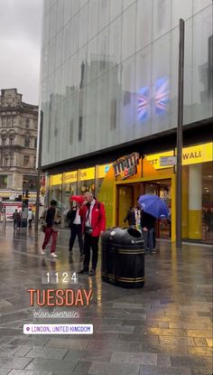 people are walking in the rain on a city street with an advertisement for tube day