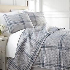 a bed with white sheets and blue plaid comforter