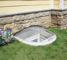 a small window in the grass next to some flowers