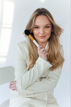 a woman holding a brush in her right hand and posing for the camera with one hand