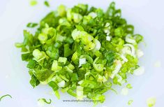 chopped green onions on a white plate with seasoning sprinkles around them