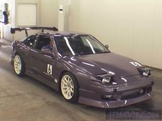 a purple car parked in a garage next to a white wall