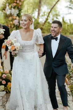 a bride and groom walking down the aisle at their outdoor wedding ceremony with flowers all around them