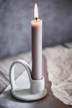 a lit candle sitting on top of a white cup