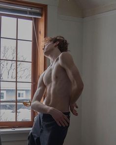 a shirtless man standing in front of a window with his hands on his hips