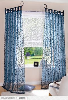 a living room with blue curtains and a white chair in front of a large window