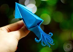 a blue origami bird sitting on top of a finger