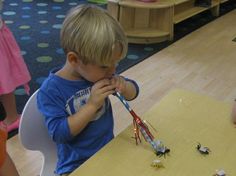 a young boy sitting at a table in front of a group of children with toothbrushes