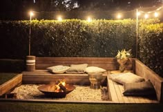 a wooden bench with pillows and lights on it in the middle of a yard area