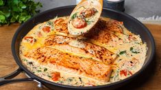 salmon with cheese and sauce in a pan on a wooden table next to some parsley