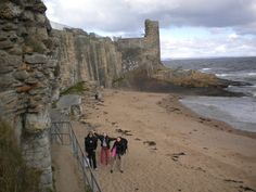 some people are walking up the stairs to an old castle by the water's edge