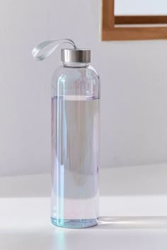 a water bottle sitting on top of a white table next to a mirror and wooden frame