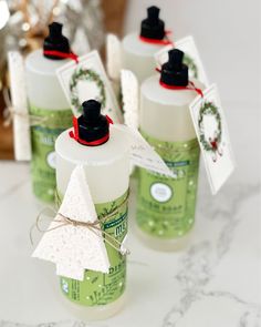 six green bottles with white labels on them sitting on a table next to a christmas tree