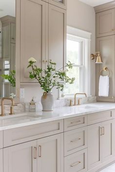 a large bathroom with two sinks and gold faucets on the countertop,