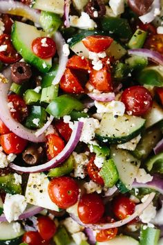 a salad with cucumbers, tomatoes, olives and feta cheese on it