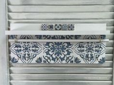 a close up of a metal door with decorative tiles on it