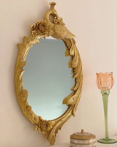 a mirror sitting on top of a white table next to a vase and candle holder