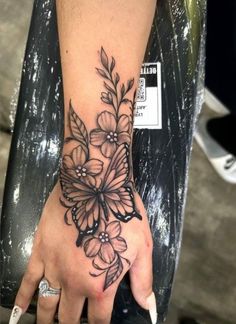 a woman's hand with a flower tattoo on the wrist and an armband