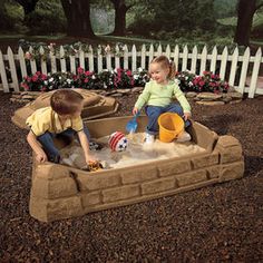 two young children playing in a sand pit