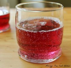 a glass filled with liquid sitting on top of a wooden table