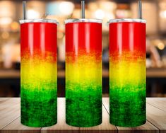 three red, yellow and green tumblers sitting on top of a wooden table in front of a bar