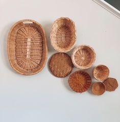 five woven baskets sitting next to each other on a white counter top with wood slices in the middle