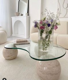 a glass table with flowers on it in a living room area next to a couch