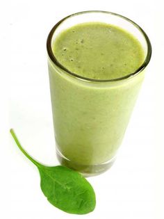 a green smoothie in a tall glass with a leaf on the side