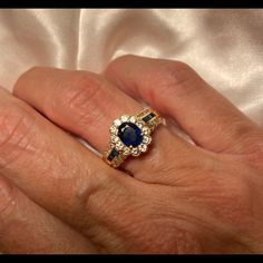 a woman's hand holding an engagement ring with blue and white stones on it