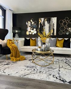 a living room with black and white furniture, gold accents and art work on the wall