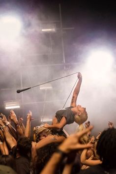 a man on stage with his arms in the air as he is lifted into the air